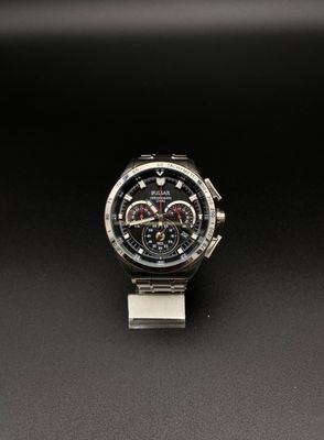 un gros plan d'une montre posée sur un support métallique, sur une surface noire