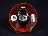 une montre posée dans un récipient rouge sur une surface noire