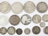 an assortment of silver and silver coins on a white surface