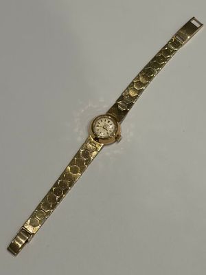 une image représentant une montre en or posée sur une surface blanche, sur fond blanc