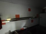 a sink in a small room with a metal shelf above it