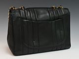 a black leather purse with a gold chain strap on a white surface
