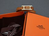 an orange box containing a pair of sandals and a brown belt