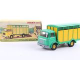 a green toy truck with a yellow trailer in front of a box