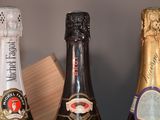 three bottles of sparkling wine are lined up on a shelf