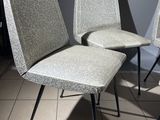 three grey chairs sitting on top of a tiled floor next to a wall