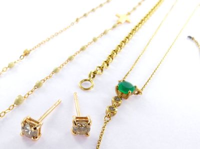 several different types of gold necklaces and earrings on a white surface