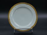 une photo d'une assiette blanche bordée d'or, posée sur un socle