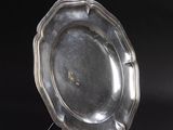 a silver plate sitting on a stand on a black surface