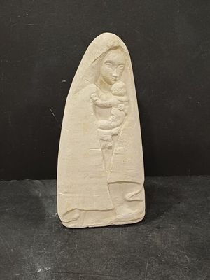 une sculpture en pierre blanche représentant une femme tenant un bébé dans ses bras