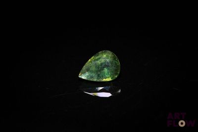 gros plan d'une pierre précieuse verte sur une surface noire