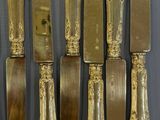 six gold plated knives and a knife holder on a table