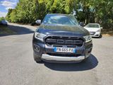 the front end of a black ford ranger parked on the side of a road