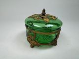 une boîte ancienne en verre vert, ornée de dorures et surmontée d'un oiseau