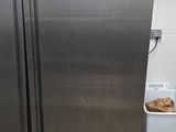 two stainless steel refrigerators in a kitchen next to a trash can