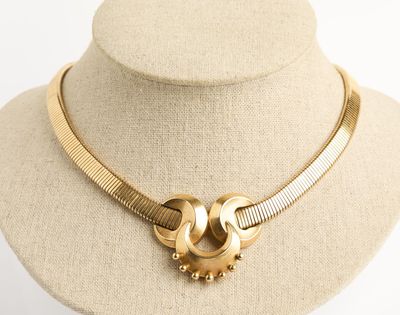 collier doré avec deux boucles et un fermoir, posé sur le cou d'un mannequin