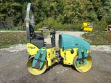 a yellow and blue road roller sitting on top of a gravel road