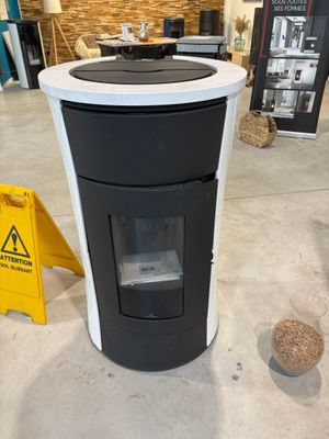une poubelle noire et blanche devant laquelle se trouve un panneau d'avertissement jaune