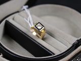 une bague en or sertie d'une pierre noire, dans un écrin