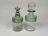 two green glass bottles with silver lids and a silver stopper