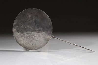 une cuillère en argent posée sur une table blanche