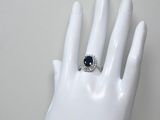 une bague sur la main d'un mannequin, sertie d'une pierre bleue