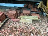 un tas de tuiles rouges par terre, à côté d'un tas de bois