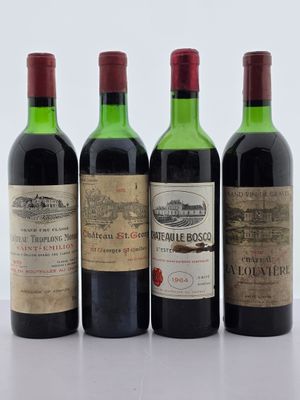 quatre bouteilles de vin sont alignées sur une surface blanche
