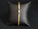 a close up of a gold bracelet on a black pillow