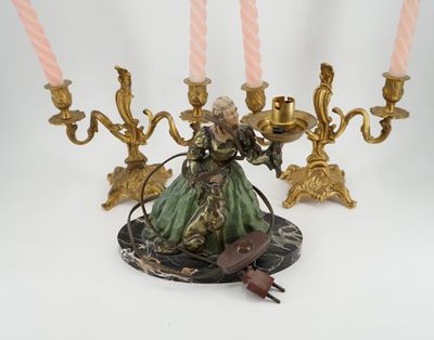 une figurine représentant une femme tenant un candélabre orné de bougies roses
