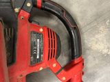 a red and black corded corded drill on the floor