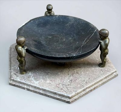 une statue représentant deux personnes debout à côté d'un grand bol