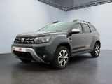 La Dacia grise est garée dans une grande pièce aux murs blancs.