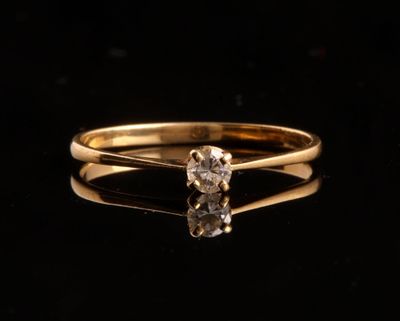 une bague en or sertie d'un seul diamant sur un fond noir