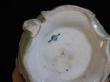 a person holding a white bowl with a blue flower on it