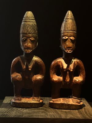 deux statues en bois représentant deux hommes, posées sur une table en bois