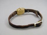 un bracelet en cuir marron sur lequel est montée une montre en or
