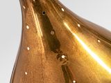 a gold vase with a white handle on a white surface