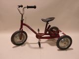 a red tricycle that is sitting on a white surface