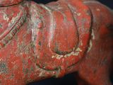 a red statue of a horse with a saddle on it ' s back