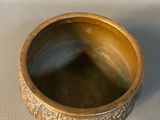 a close up of a gold bowl on a white surface