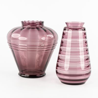 des vases en verre violet posés les uns à côté des autres sur une surface blanche