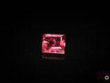 a close up of a pink diamond on a black surface