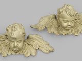 a pair of carved angel heads on a gray background