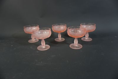 quatre verres à pied roses posés sur une table noire