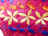 close up of a woman ' s red dress with colorful embroidered flowers on it
