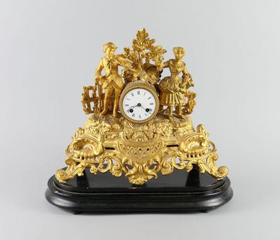 une horloge dorée posée sur un socle noir, avec un fond blanc