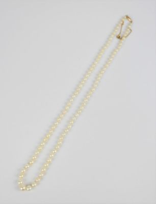 un collier de perles blanches avec un fermoir en or sur fond blanc
