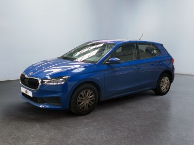 Une voiture bleue est garée dans une pièce aux murs blancs.