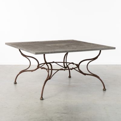 une table en fer avec un plateau en béton et des pieds en fer